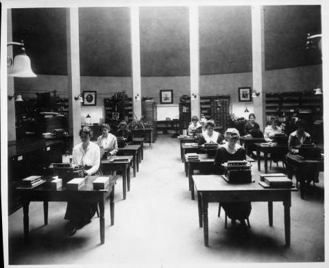 Interior photo of the apse, showing State Library staff at work on their typewriters.  Circa 1900.