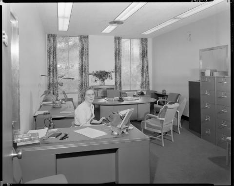 Capitol annex office circa 1952. Female secretary shown at desk using typewriter. 1950s era office equipment, file cabinets, and furniture shown (black and white photo).